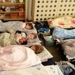 Na zdjęciu grupa śpiących dzieci. Przy leżakach stoją koszyki na ubrania.jpg