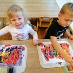 Dzieci siedzą  przy stoliku, malują farbami akwarelowymi. Rysunek przedstawia jesienne drzewa..jpg