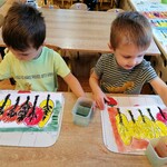 Dzieci siedzą przy stoliku, malują farbami tło do pracy plastycznej . Praca przedstawia jesienne drzewa..jpg