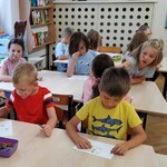 Dzieci siedzą przy stolikach z Sudoku.