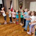 Na zdjęciu widać grupę dzieci ustawioną w kole. Dzieci wykonują polecenia instruktora.