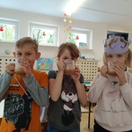 Troje dzieci z uśmiechami na twarzy piją dodatkową porcję soku.