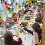 Wigilia w grupie II - Odświętnie ubrane dzieci siedzą przy świątecznym stole.
