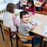 Dzieci przy stolikach uzupełniają kartę pracy.jpeg